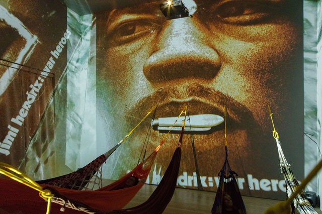 Hélio Oiticica. Installation view. CC5 Hendrix-War,1973.Thirty-three 35mm color slides transferred to digital slideshow, sound, and hammocks. Site Specific Collections of César and Claudio Oiticica and Neville D’Almeida. Whitney Museum of American Art, New York, N.Y. Photograph by Oto Gillen